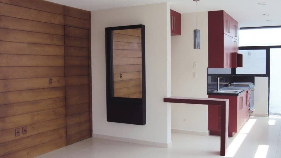 Interior con muro de madera, espejo y cocina en tono vino